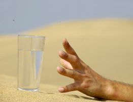 A hand reaching for a glass of water in the desert dehydration